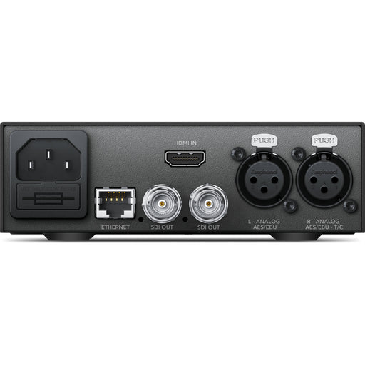 The Blackmagic Design Teranex Mini HDMI to SDI 12G Converter is a compact, rectangular device with a matte black finish. The front panel features a USB port and ventilation grilles, while the rear panel includes an HDMI input, two 12G-SDI outputs, an Ethernet port, and XLR audio inputs. This design facilitates professional video and audio signal conversion in broadcast and post-production environments.