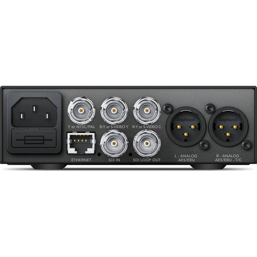 The Blackmagic Design Teranex Mini SDI to Analog 12G Converter is a compact, rectangular device with a matte black finish. The front panel features a USB port and ventilation grilles, while the rear panel includes a 12G-SDI input, a loop-through SDI output, component, S-Video, and composite analog video outputs, an Ethernet port, and XLR audio outputs. This design facilitates professional video and audio signal conversion in broadcast and post-production environments.