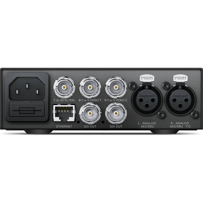 The Blackmagic Design Teranex Mini Analog to SDI 12G Converter is a compact, rectangular device with a matte black finish. The front panel features a USB port and ventilation grilles, while the rear panel includes component, S-Video, and composite analog video inputs, two 12G-SDI outputs, an Ethernet port, and XLR audio inputs. This design facilitates professional video and audio signal conversion in broadcast and post-production environments.