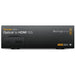 The Blackmagic Design Teranex Mini Optical to HDMI 12G Converter is a compact, rectangular device with a matte black finish. The front panel features a USB port and ventilation grilles, while the rear panel includes a 12G-SDI input, an optional optical fiber input, an HDMI output, two full-size XLR audio outputs, an Ethernet port, and a standard IEC power input. This design facilitates the conversion of high-resolution SDI or optical fiber signals to HDMI, supporting video formats up to DCI 4K at 60p.