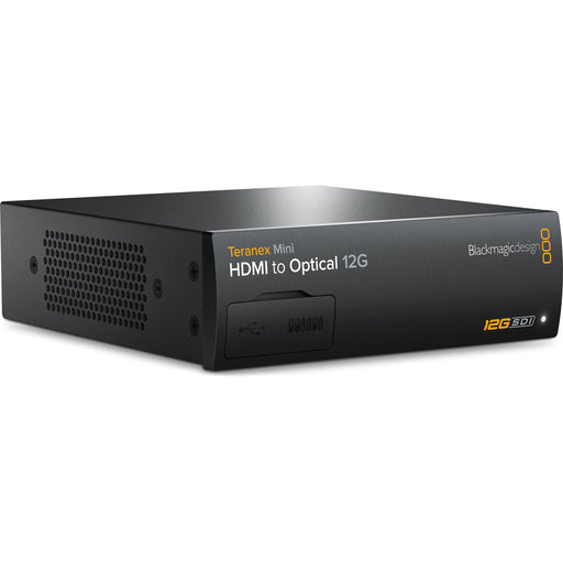 The Blackmagic Design Teranex Mini HDMI to Optical 12G Converter is a compact, rectangular device with a black finish. The front panel features a USB port and ventilation grilles, while the rear panel includes an HDMI input, a 12G-SDI output, an optional optical fiber output slot, two full-size XLR audio inputs, an Ethernet port, and a standard IEC power input. This design facilitates the conversion of high-resolution HDMI signals to 12G-SDI or optical fiber, supporting video formats up to DCI 4K at 60p.